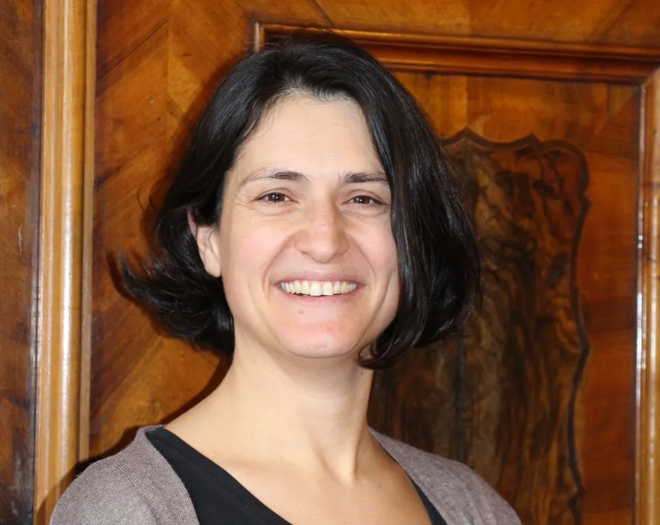 Portrait einer Frau mit dunklen mittellangen Haaren, strahlendem Lachen  vor barocker Türe