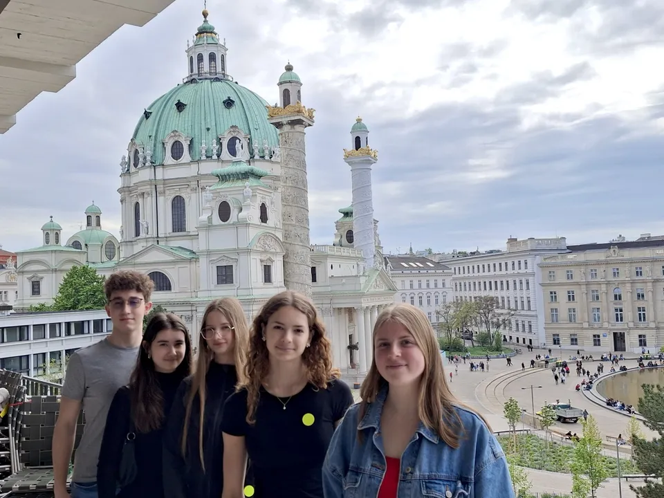 Gruppe von fünf Jugendlichen auf einem Balkon vor der Karlskirche posierend