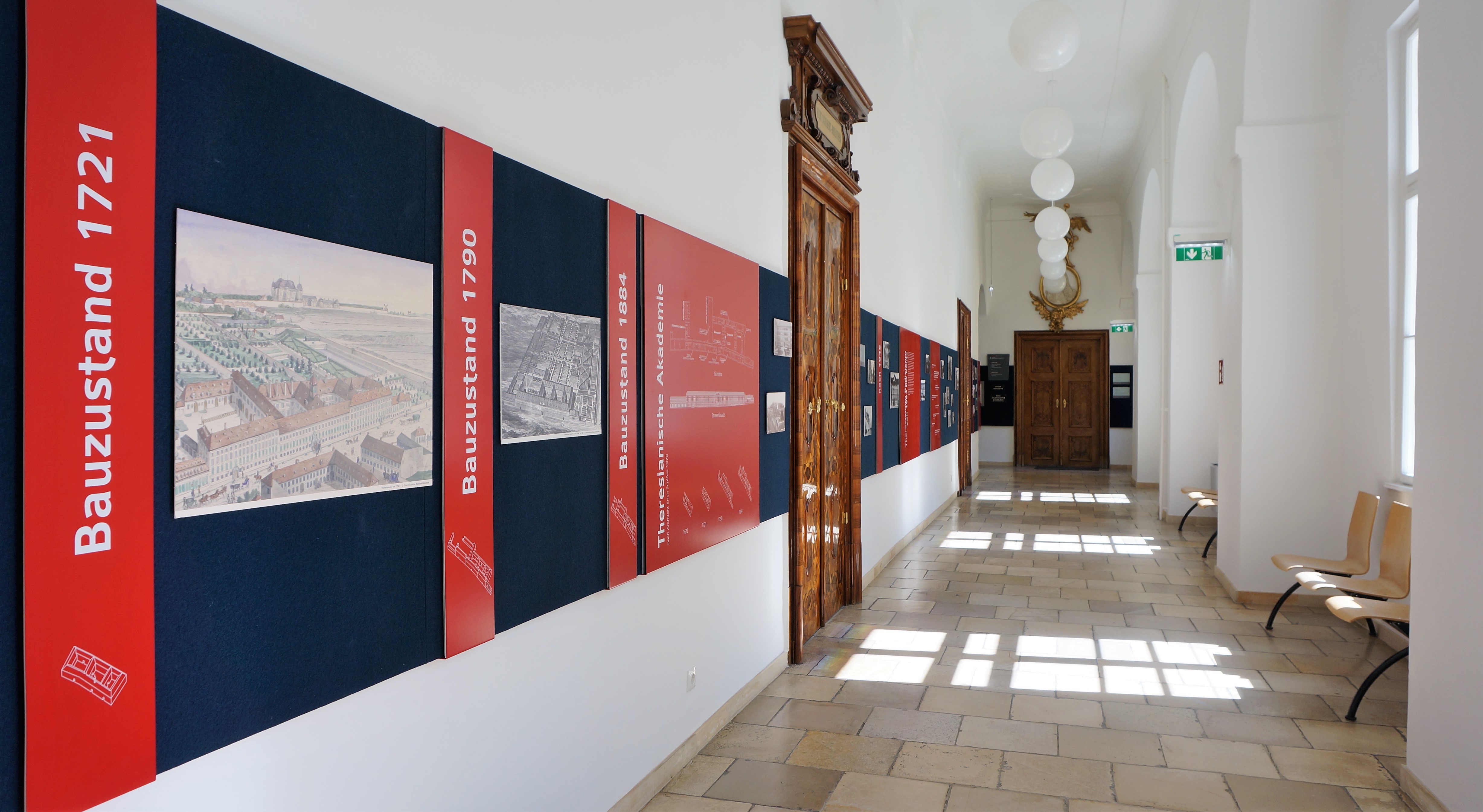 Historischer Gang mit blau-roten Wandpaneelen mit historischen Abbildungen.