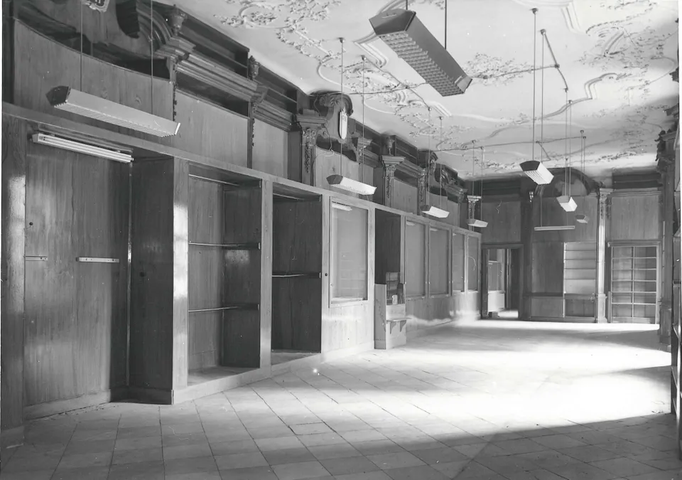schwarz weiß Foto eines leeren historischen Raumes mit Stuckdecke und Wandverbauten