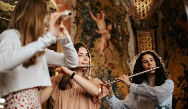 Drei Frauen Querflöte spielend vor barockem historischem Hintergrund