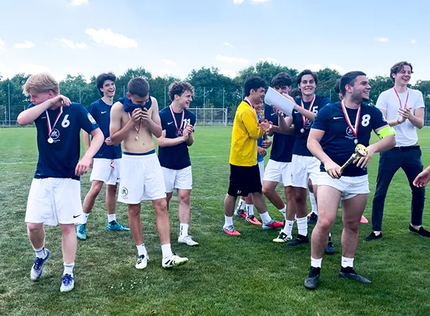 Gruppe von jungen Burschen in Fussballdressen im Freudentaumel mit Medaillen um den Hals.