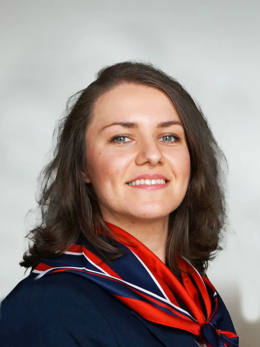 Portraitfoto einer sympathischen jungen Frau mit dunklen langen gewellten Haaren mit freundlichem Lachen und elegantem rot blauem Seidentuch