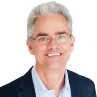 A professional man wearing glasses and a suit, smiling confidently
