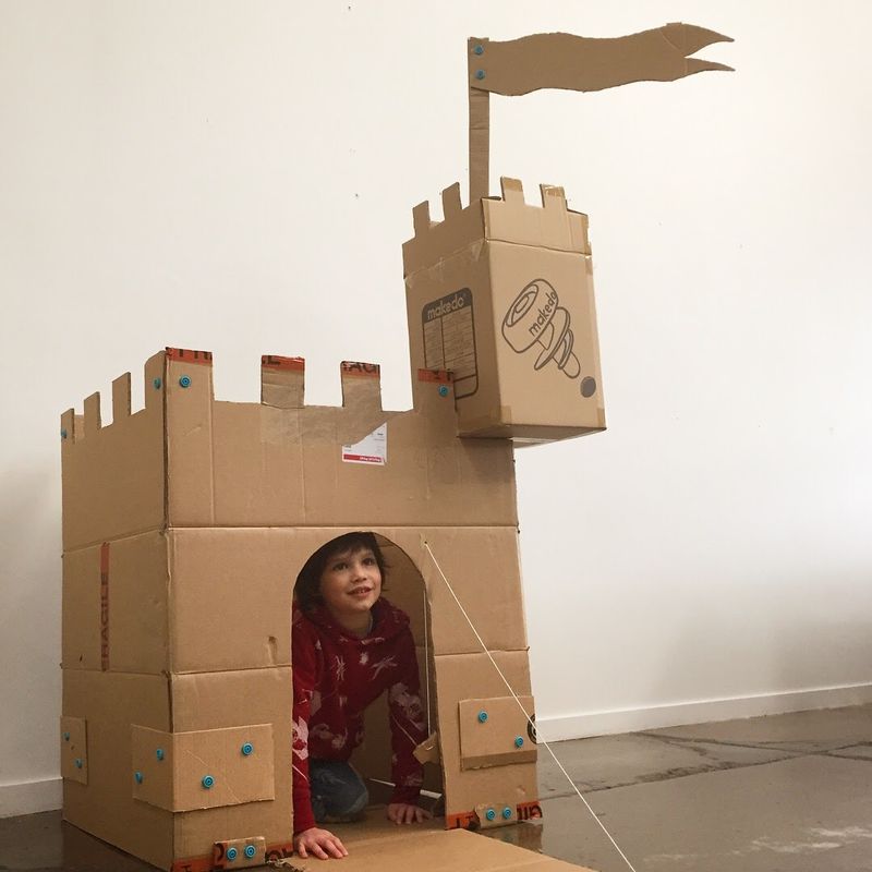 Young boy looking through the open drawbridge of a cardboard Makedo castle