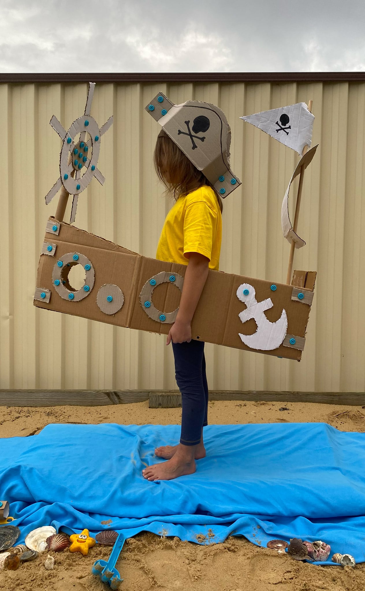 Child standing in a cardboard Makedo pirate ship creation.