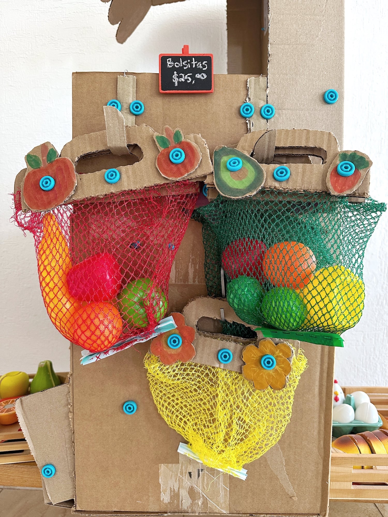 Cardboard and reclaimed fruit nets turned into pretend play market stall storage bags using Makedo.