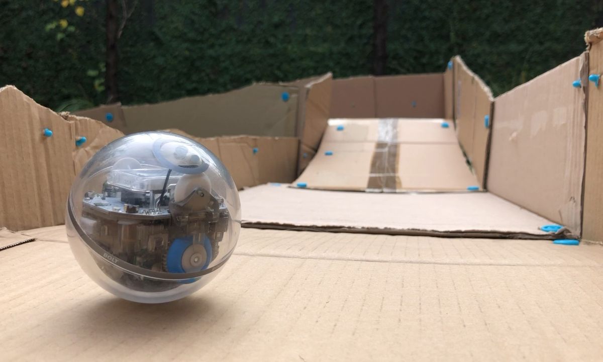 Sphero robot poised at the top of a long cardboard ramp on a race track made with Makedo