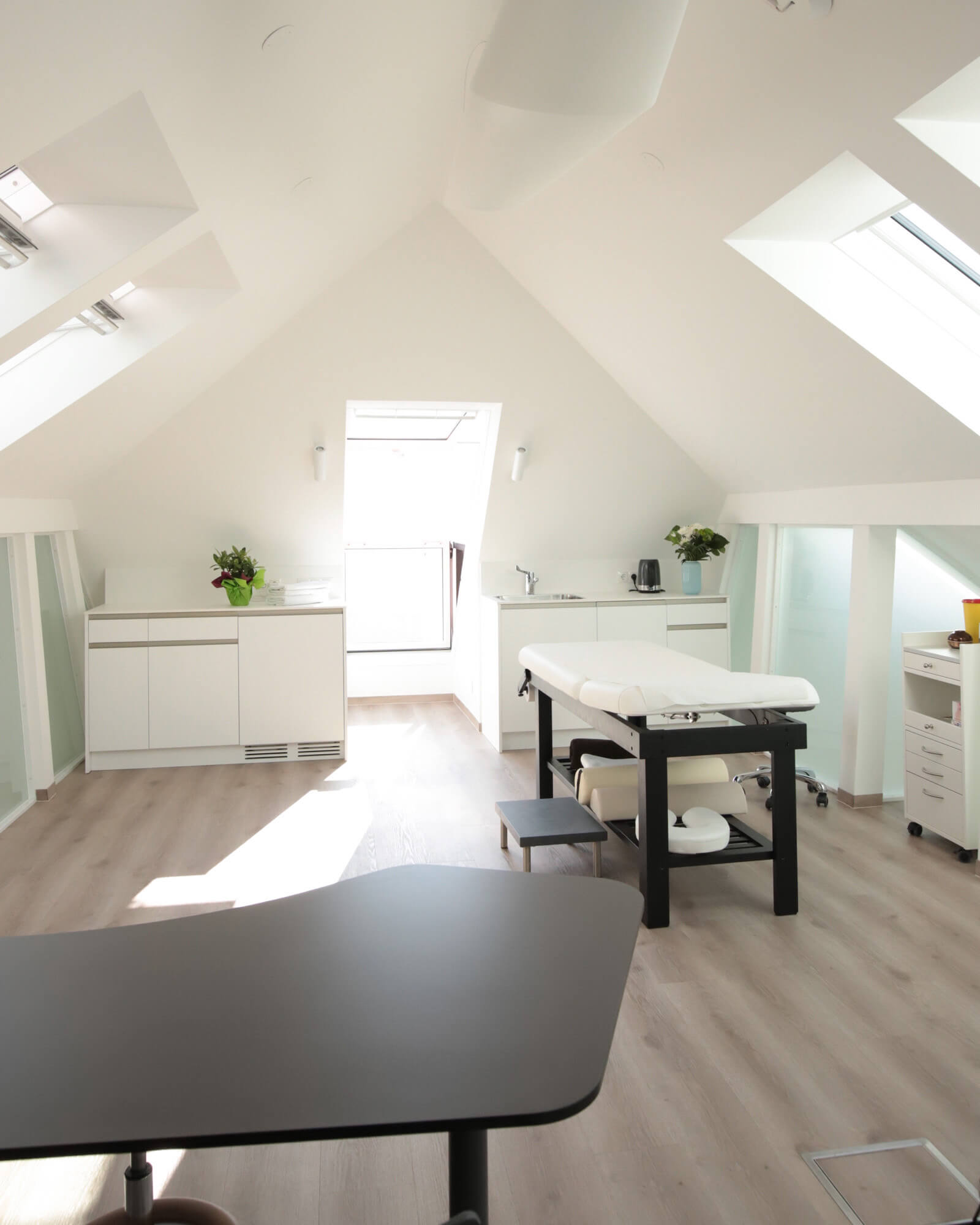 Moderner Behandlungsraum mit Tageslicht und einem Behandlungstisch in der Ordination RiederKager in Krems.