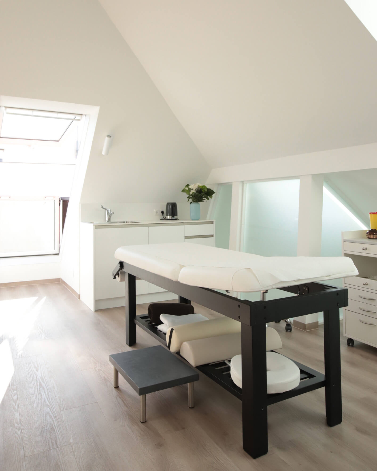 Heller Behandlungsraum mit einem Behandlungstisch in der Ordination RiederKager in Krems.
