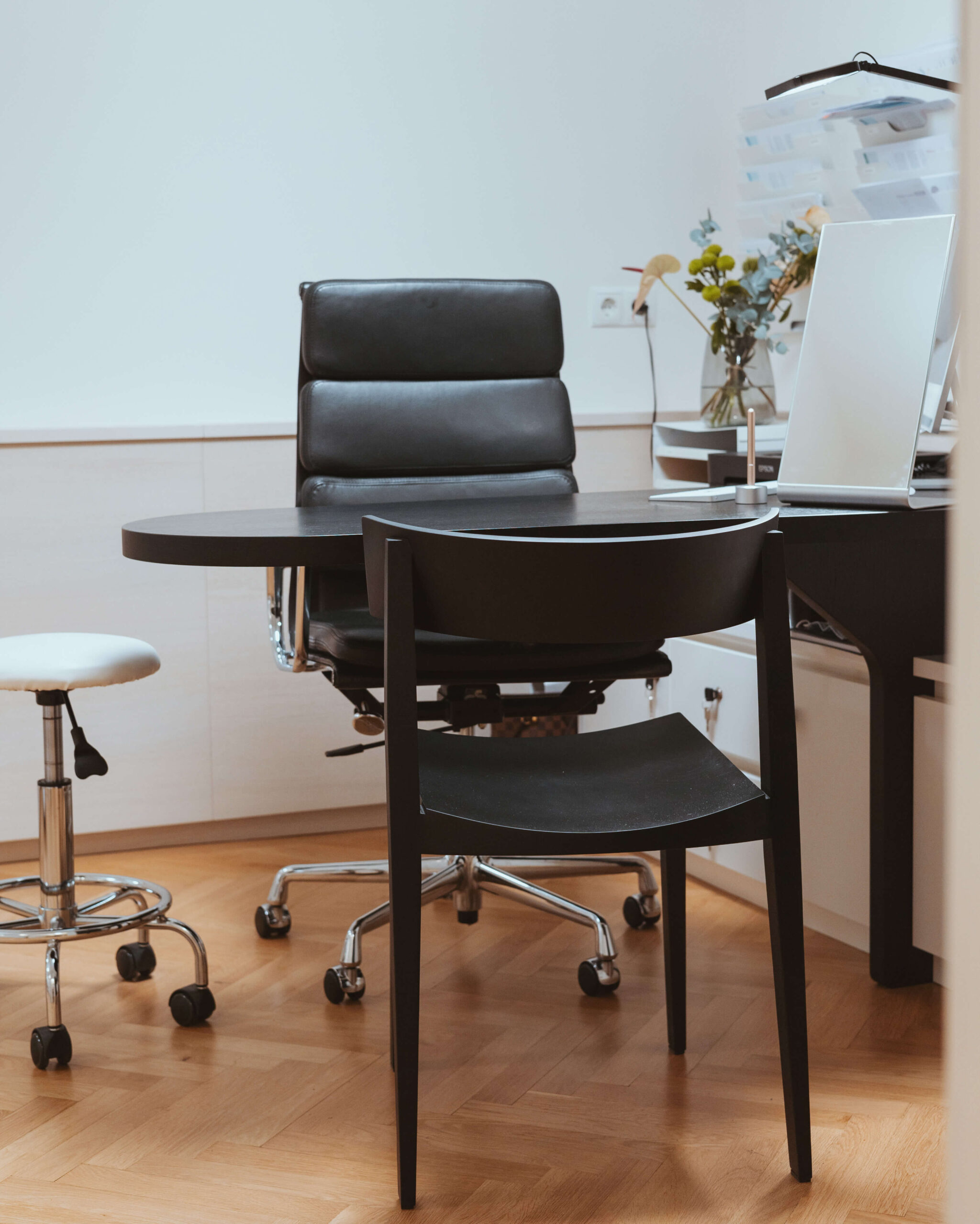 Beratungsbereich mit schwarzem Schreibtisch und Stühlen in der Ordination RiederKager.