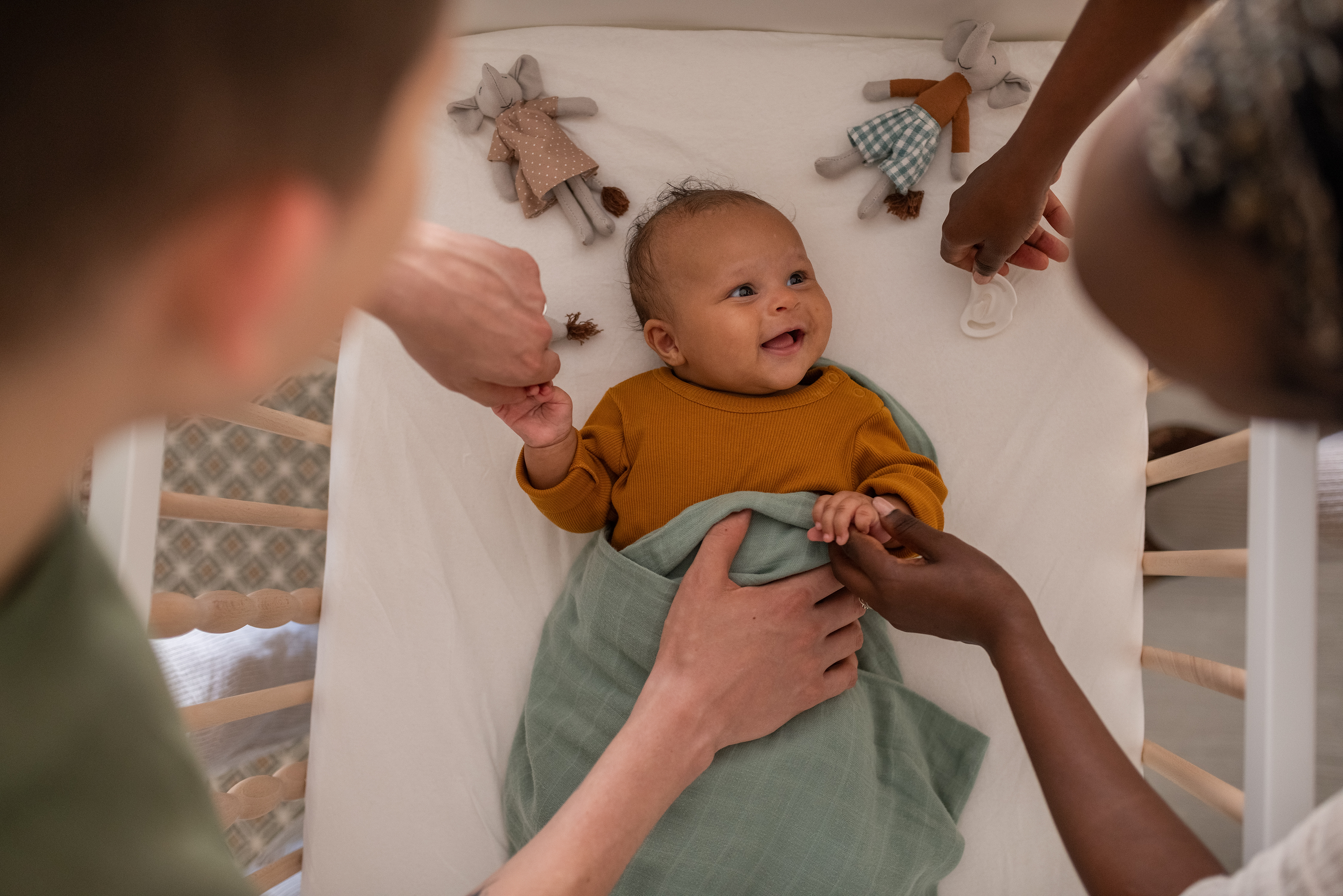 Baby smiling at parents while resting in crib