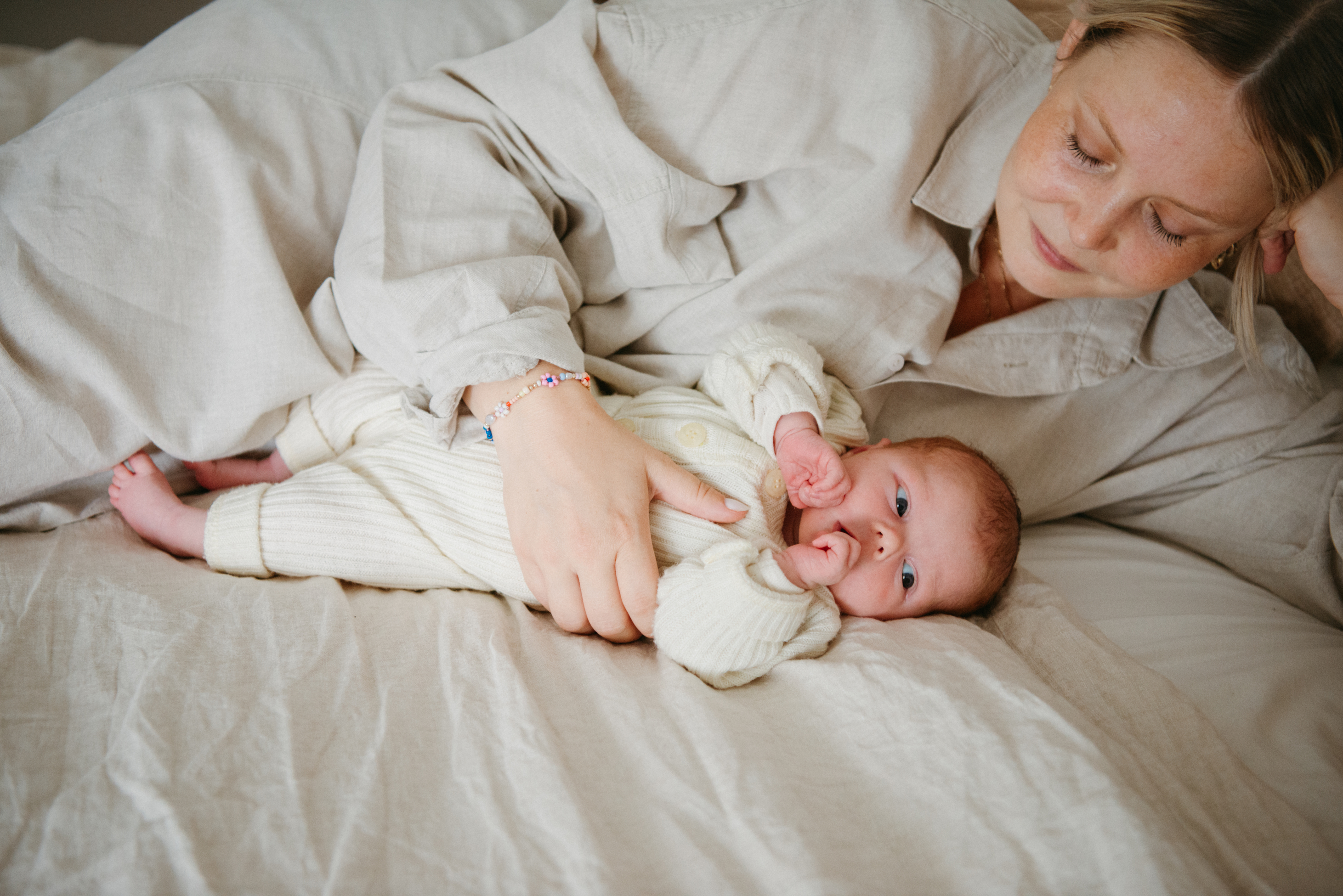 Mother holding newborn baby in bed