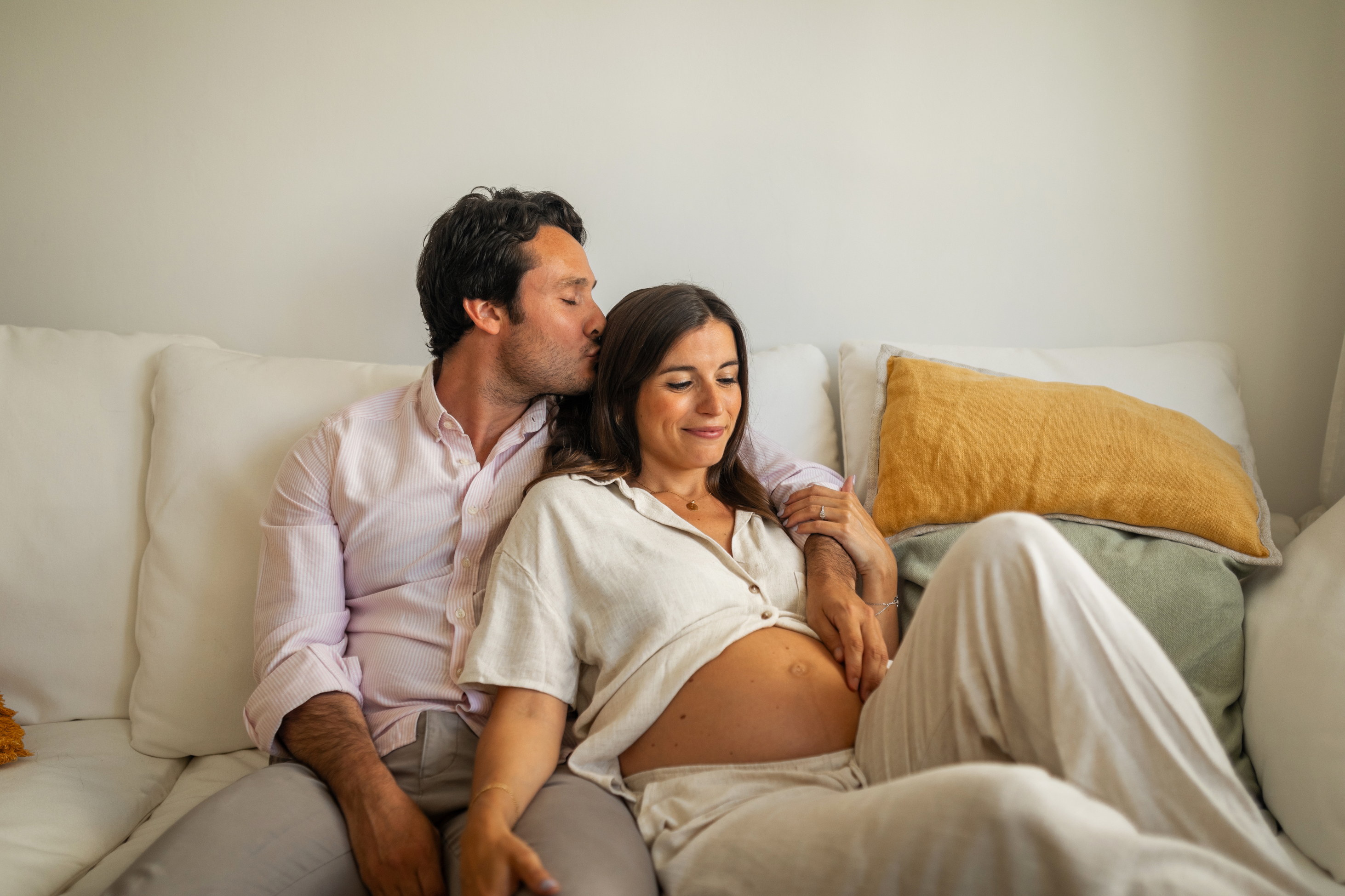 pregnant woman and partner sitting on couch relaxing together