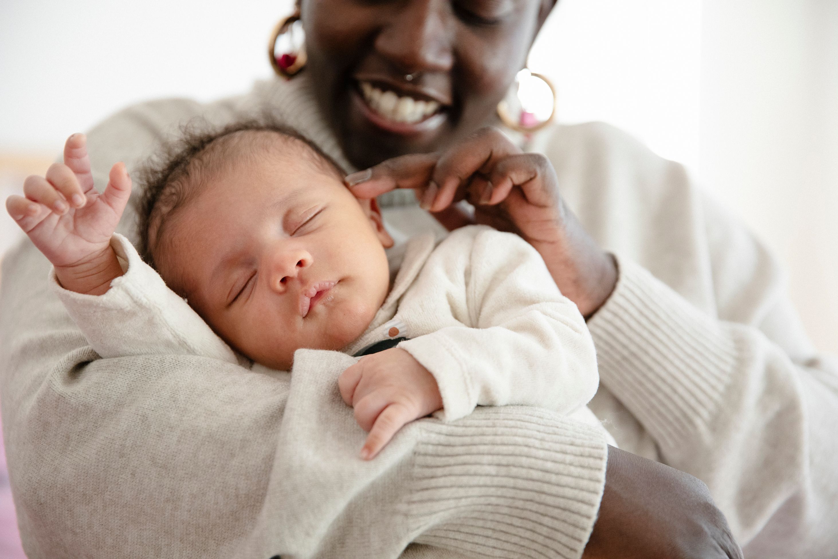 A smiling mother cradles her sleeping baby