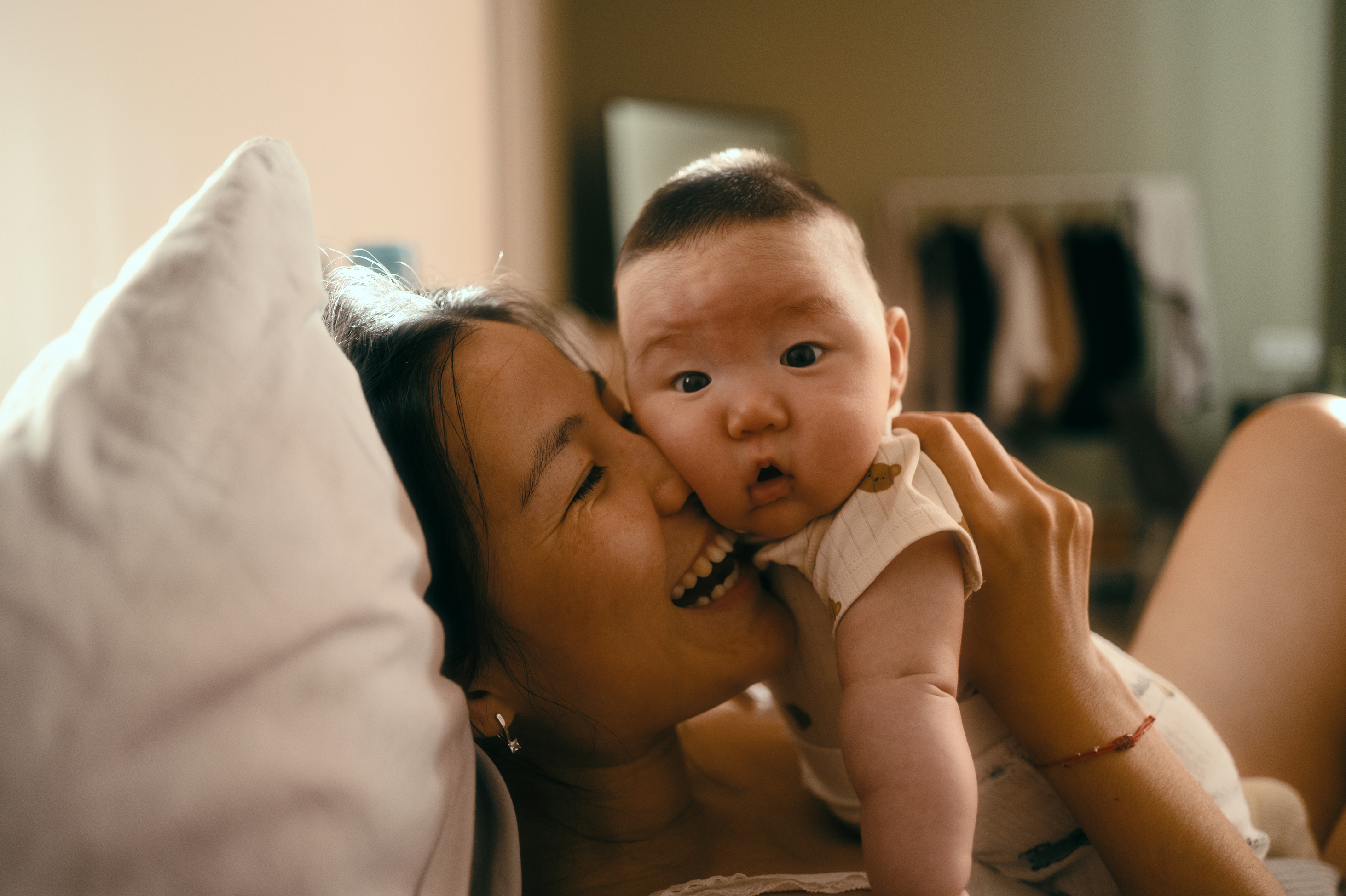 Mother smiling while snuggling baby in bed