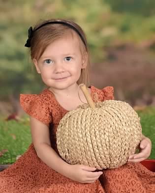 Smiling toddler holding a pumpkin