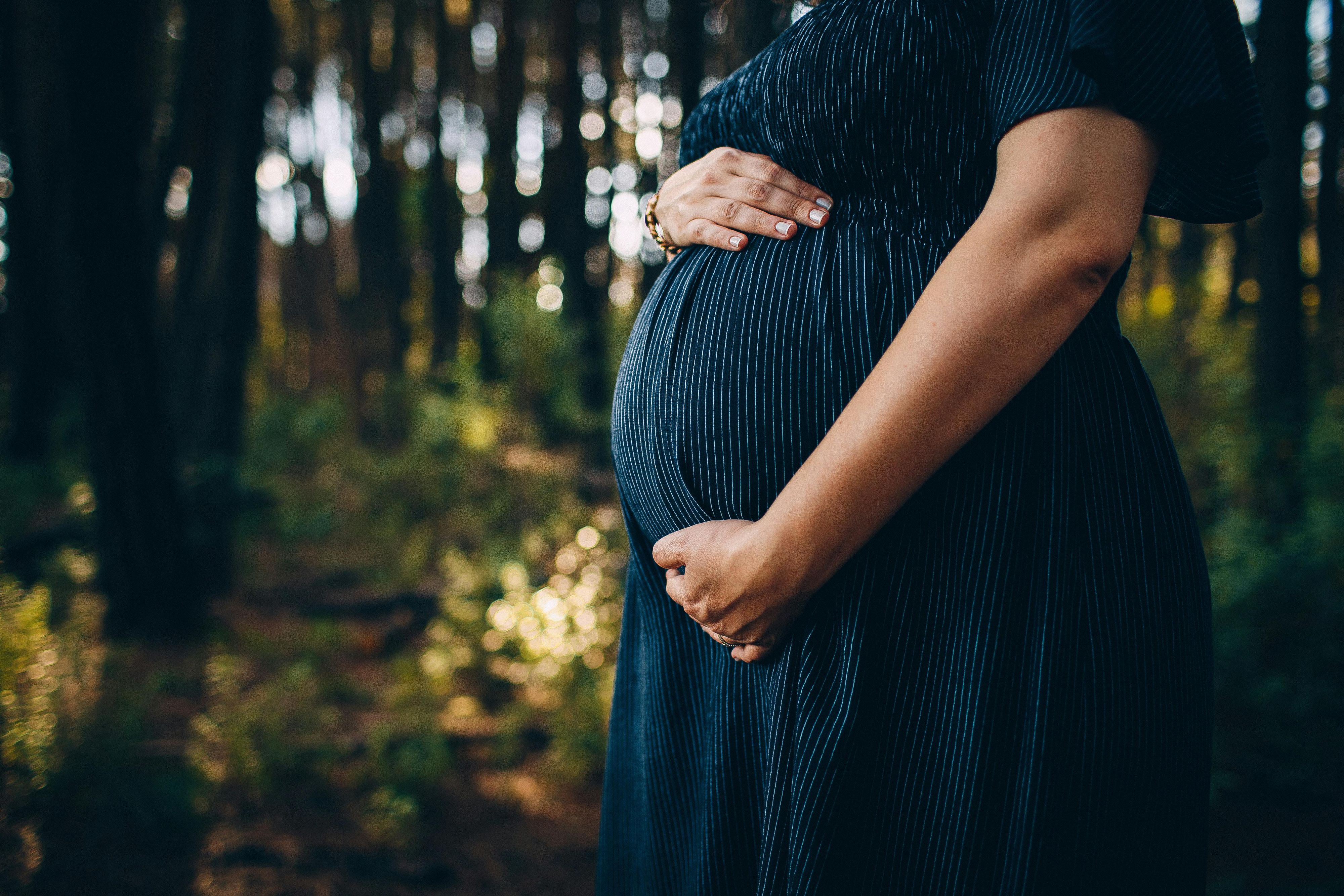 A pregnant women holding her stomach in a navy dress