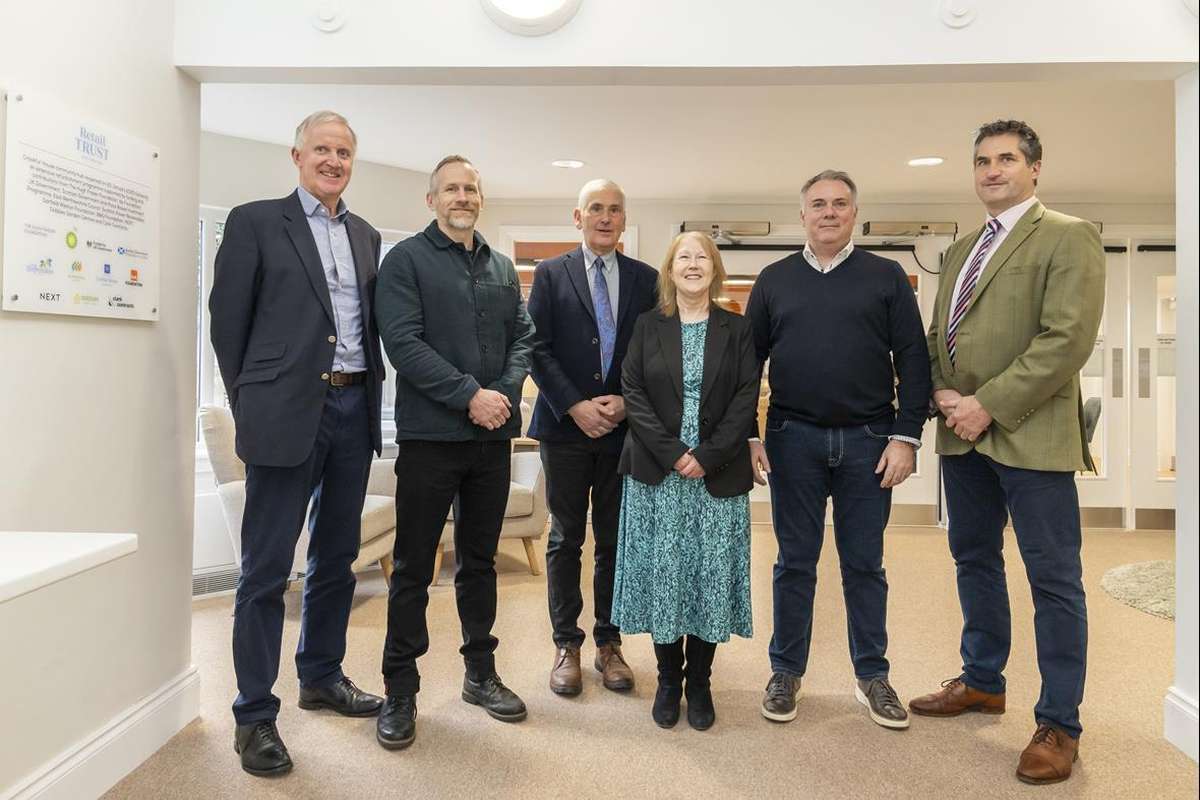 Six smiling professionals, five men and one woman, pose in a bright office with a 'Retail TRUST' sign.