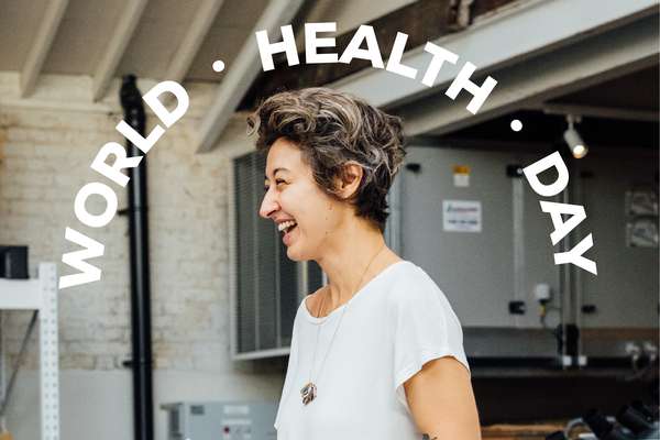 Profile view of a happy woman with short curly hair laughing, overlaid with "WORLD HEALTH DAY" text in a white arc.