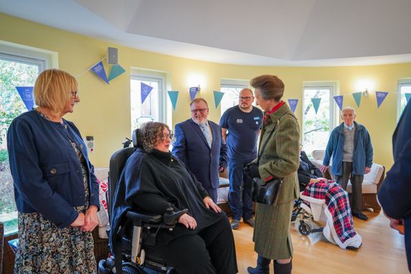 A woman in a wheelchair interacts with a group of people in a room decorated with pennant banners.