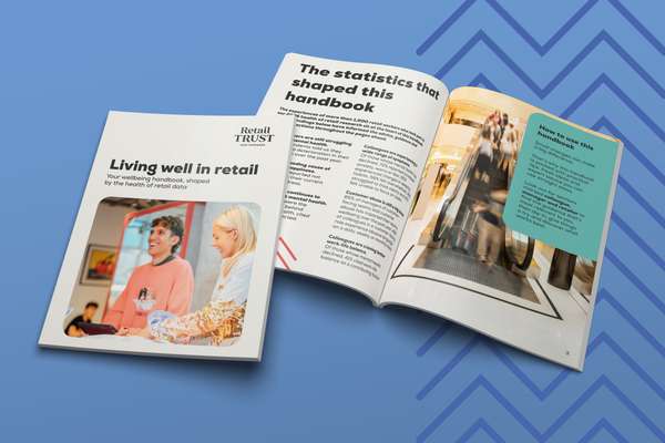 Two open handbooks on retail wellbeing and statistics, featuring a smiling couple and people on an escalator, on a blue patterned background.