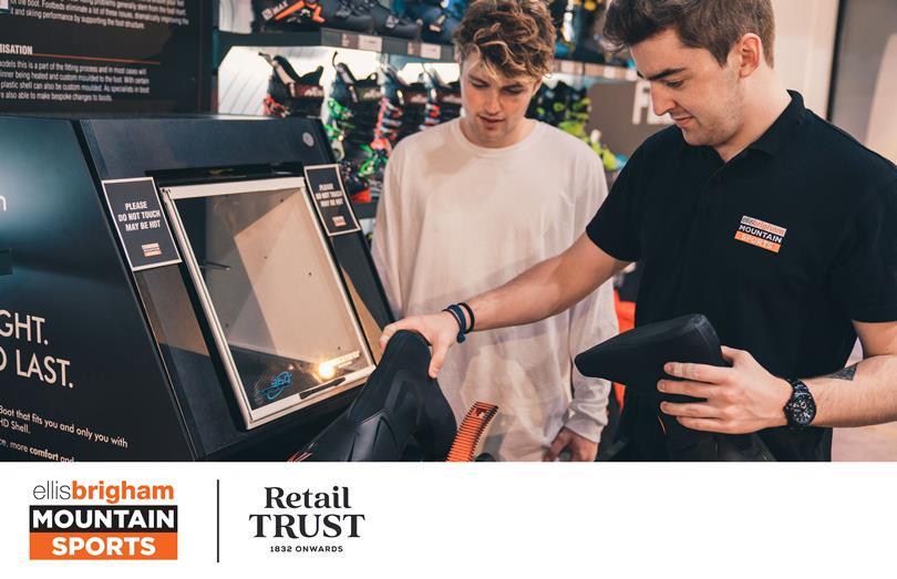 A staff member at Ellis Brigham Mountain Sports assists a customer, heating a ski boot liner in a fitting machine.