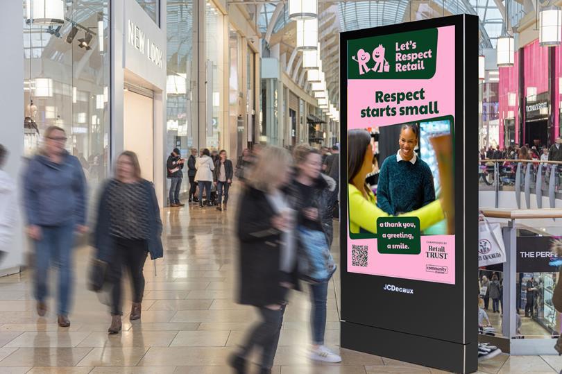 A digital screen in a bustling mall advertises "Let's Respect Retail" with a smiling woman and text "Respect starts small." Blurry shoppers walk past.
