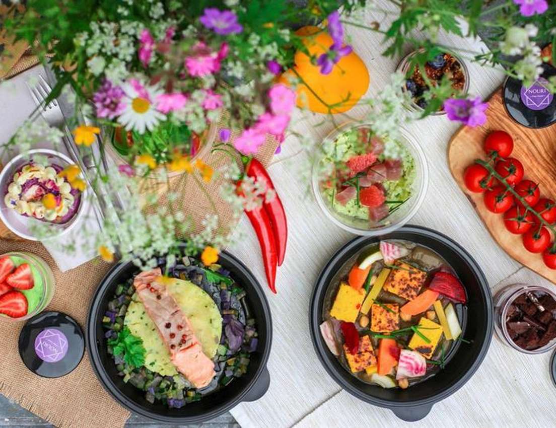 A colorful table setting featuring diverse dishes with salmon, vegetables, fresh strawberries, and cherry tomatoes, surrounde