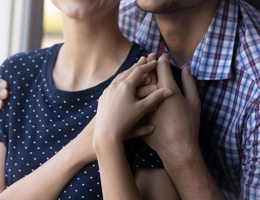 Hands of a couple embracing tightly, conveying comfort and affection.