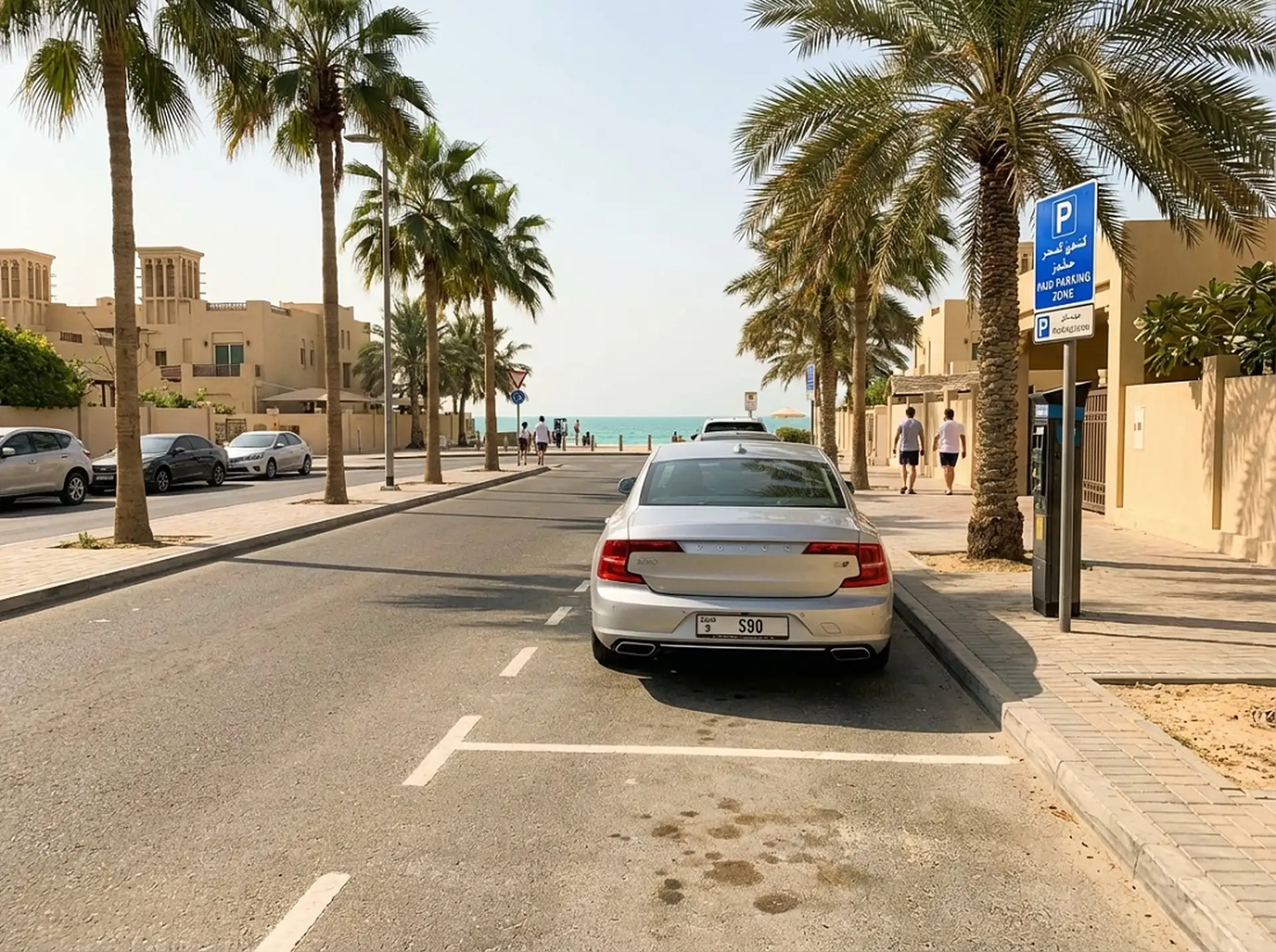 Street lined with palm trees leading to a beach. A silver car is parked on the right. People are walking, and a parking sign is visible.