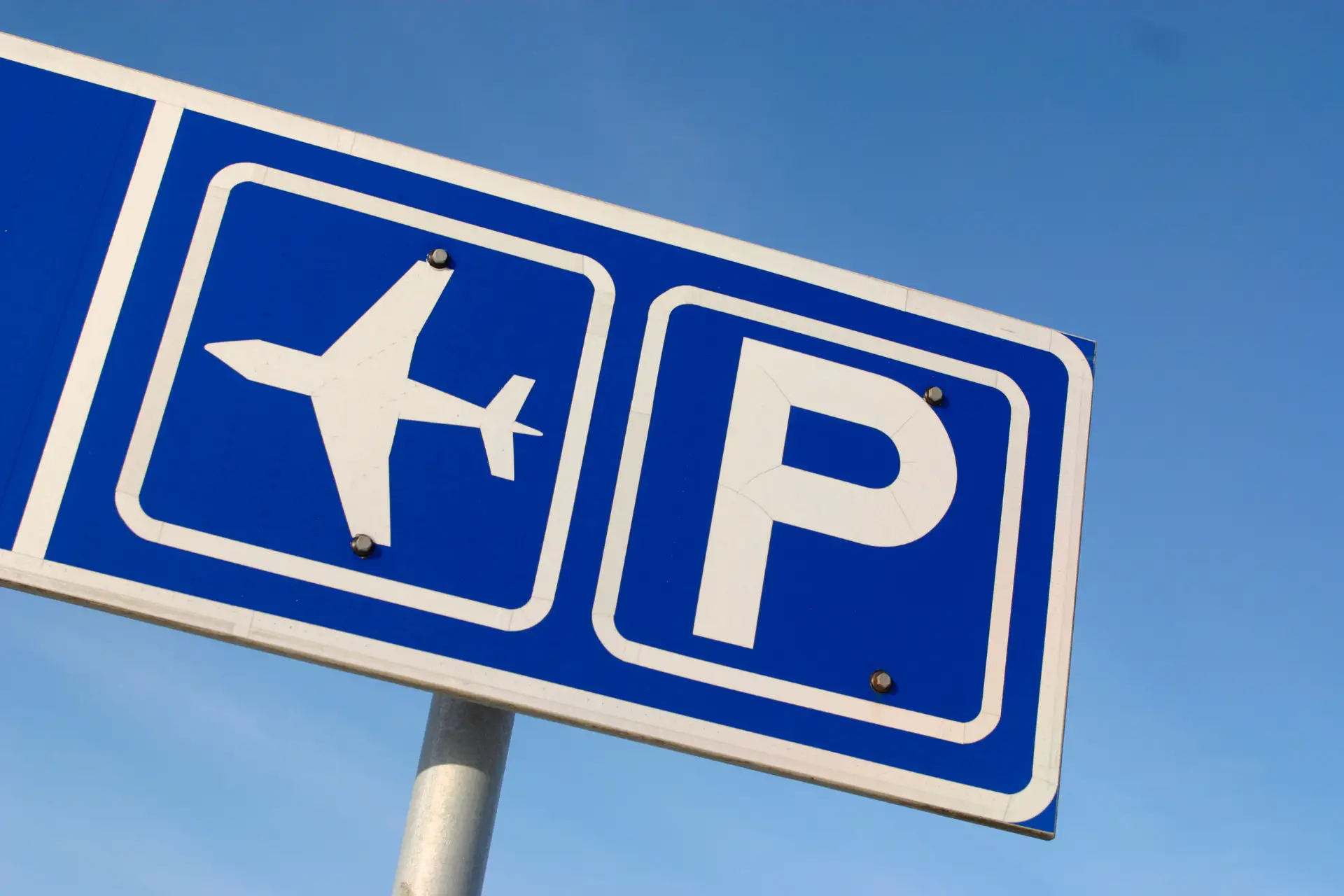 Blue airport parking sign with an airplane icon and a large 'P' against a clear sky.