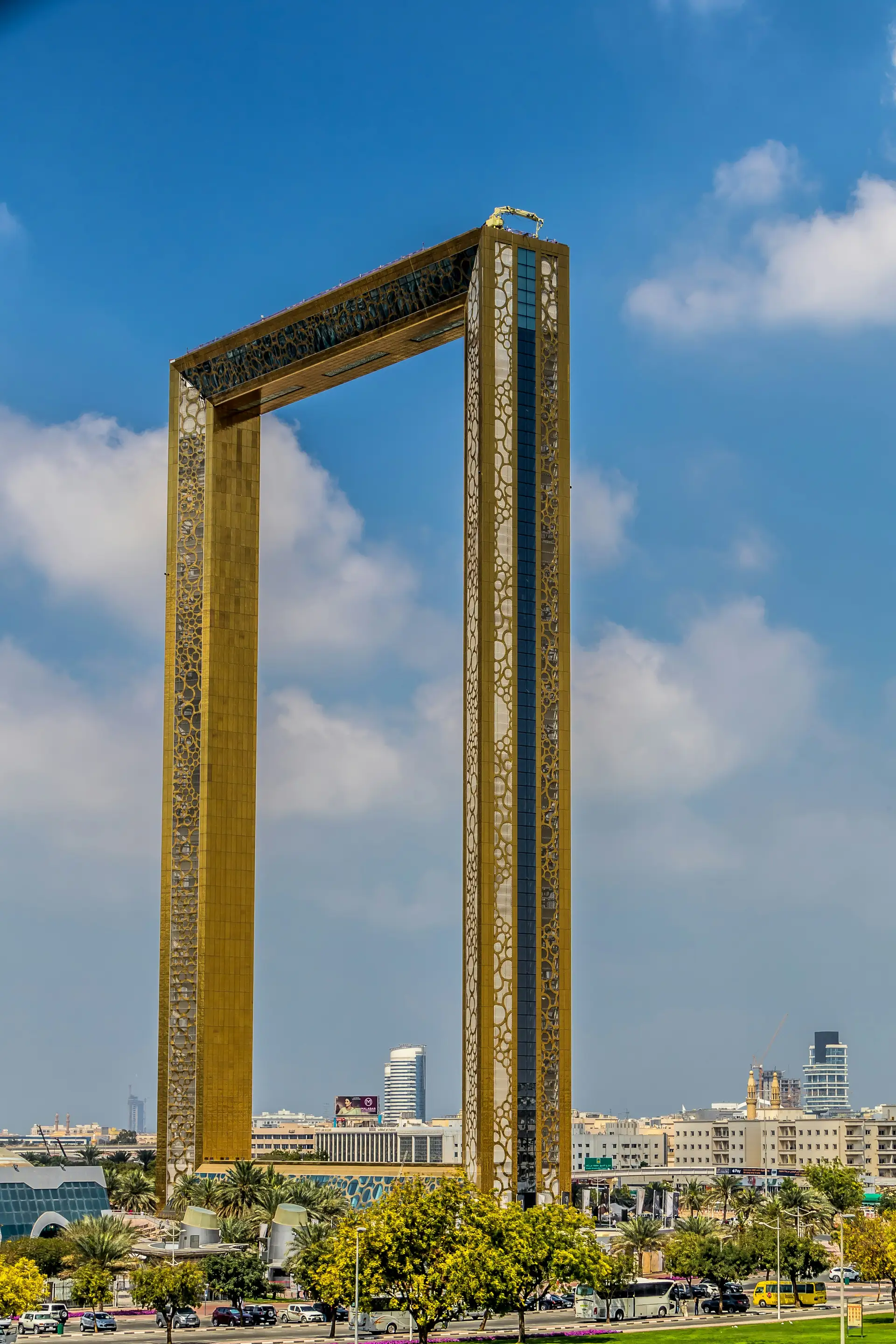 The Dubai Frame, a large rectangular structure, towers over the cityscape with a clear blue sky in the background.