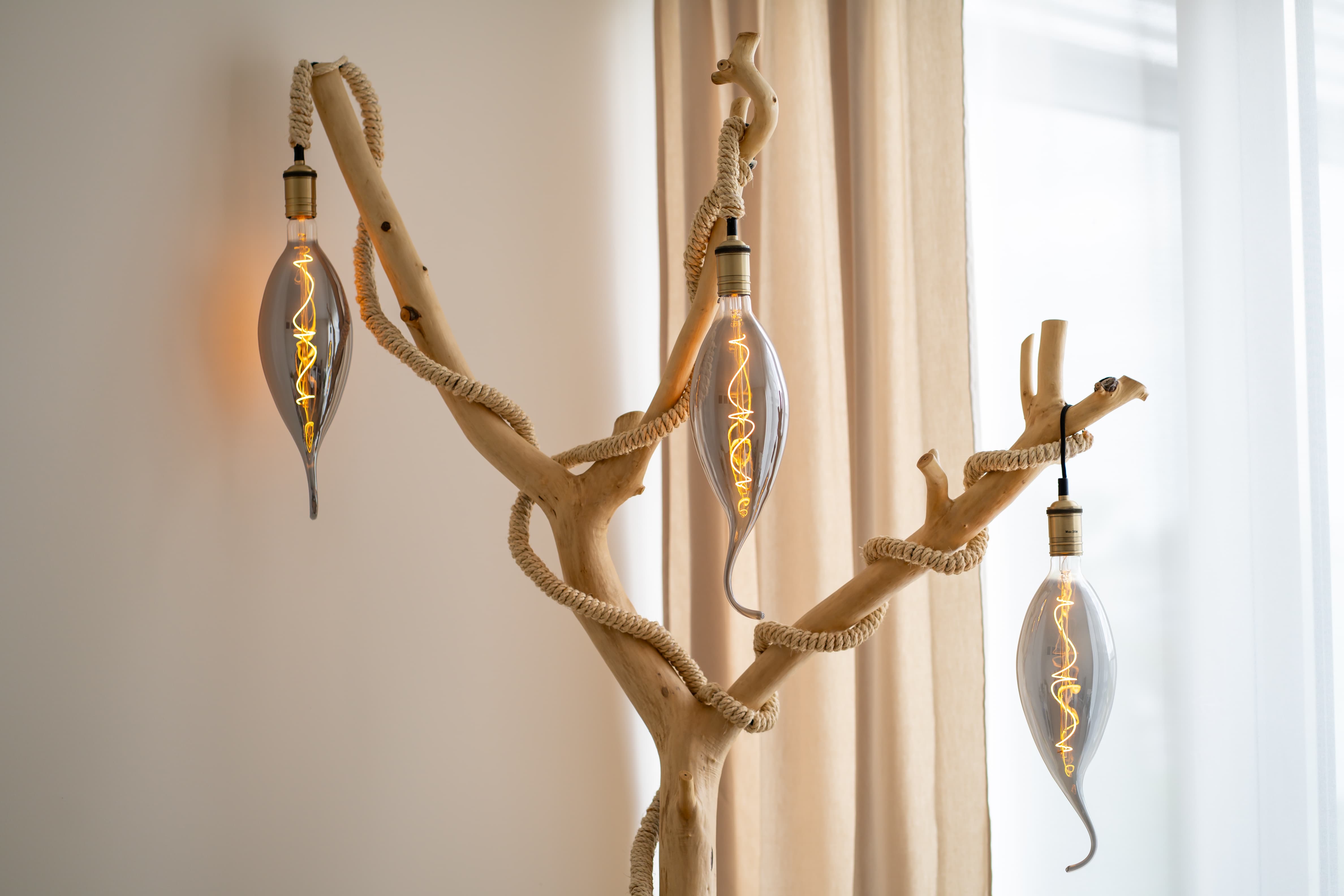 Dekorative Lampe aus naturbelassenem Holz und Seil mit drei leuchtenden Glasbirnen
