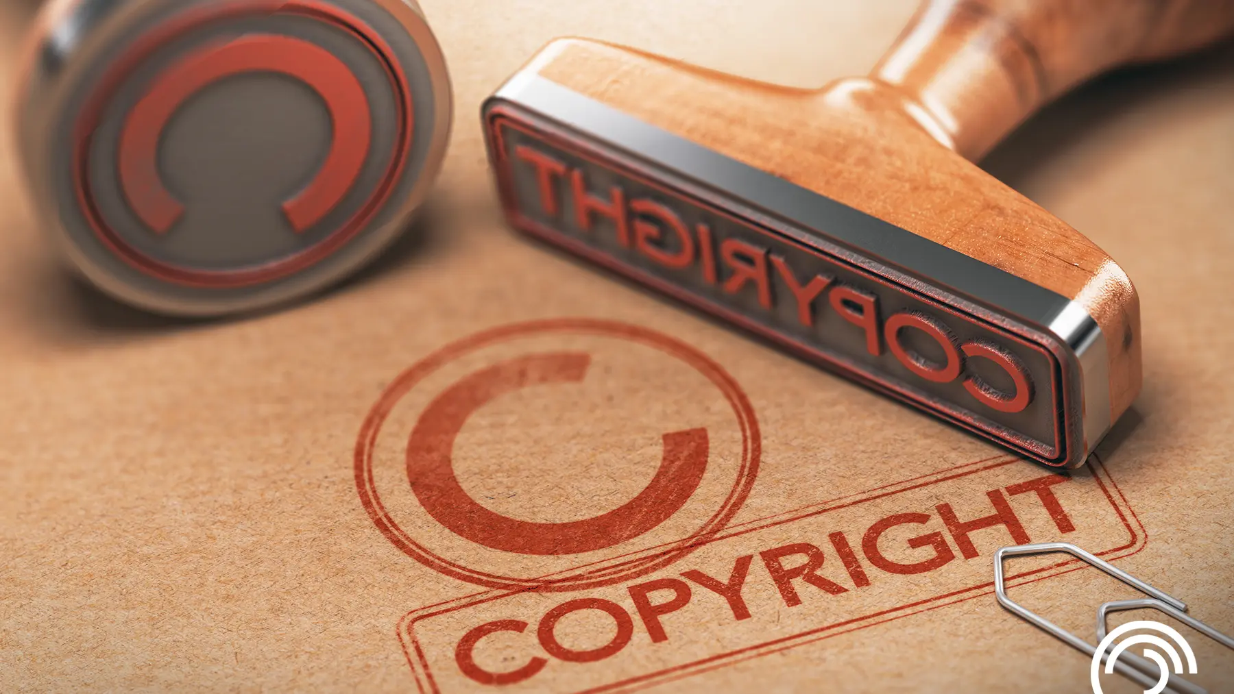 Wooden copyright stamps on paper, with a red copyright symbol and a paperclip.