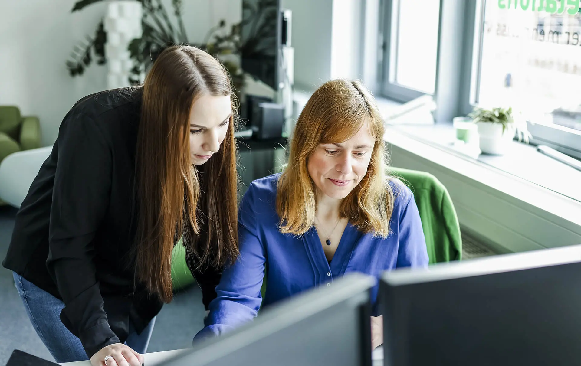 Zwei Analystinnen besprechen gemeinsam eine Analyse am Bildschirm