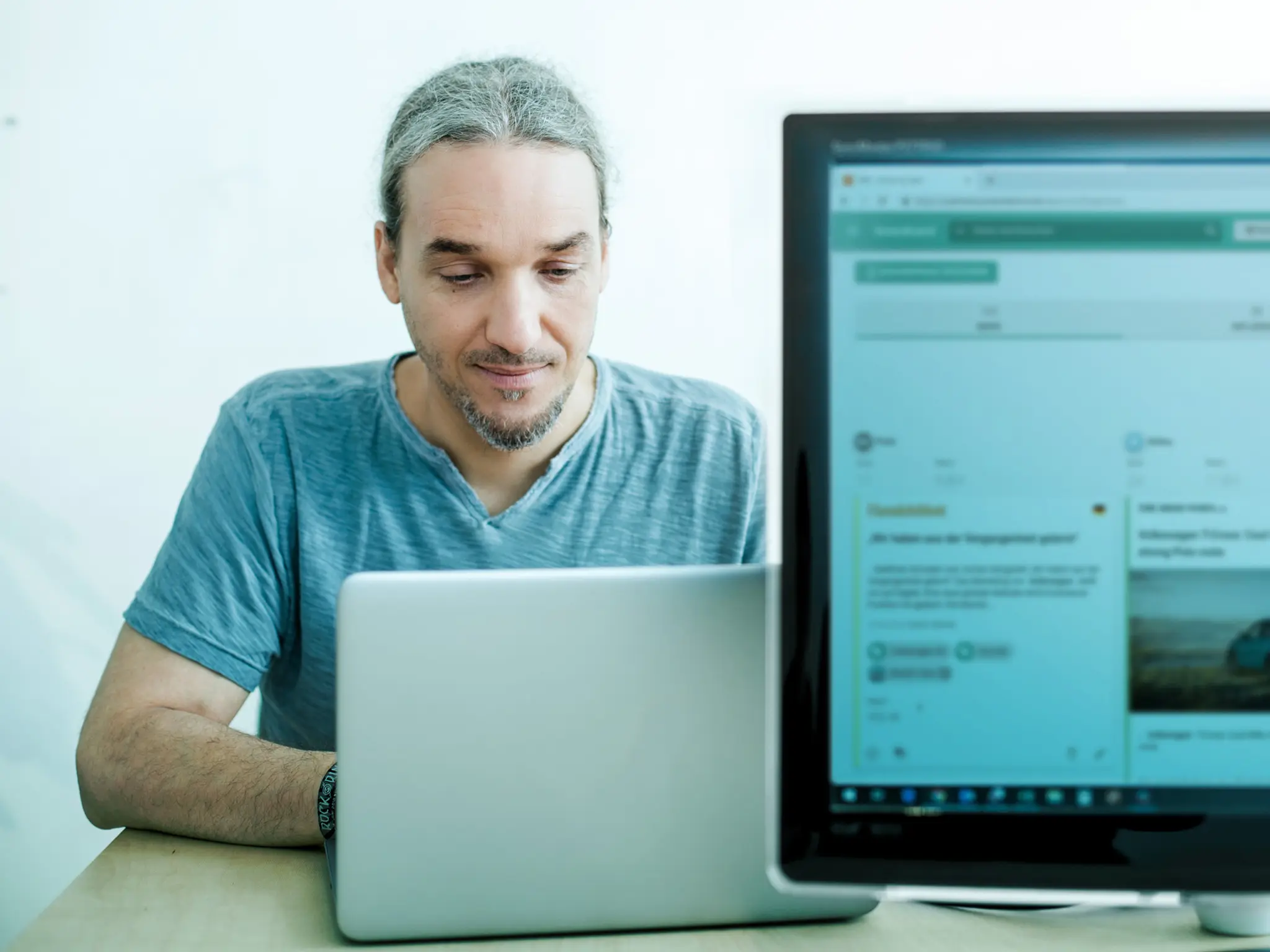 Ein Pressereferent liest morgens den täglichen Medienspiegel auf seinem Laptop – auf einem Bildschirm daneben ist NewsRadar geöffnet