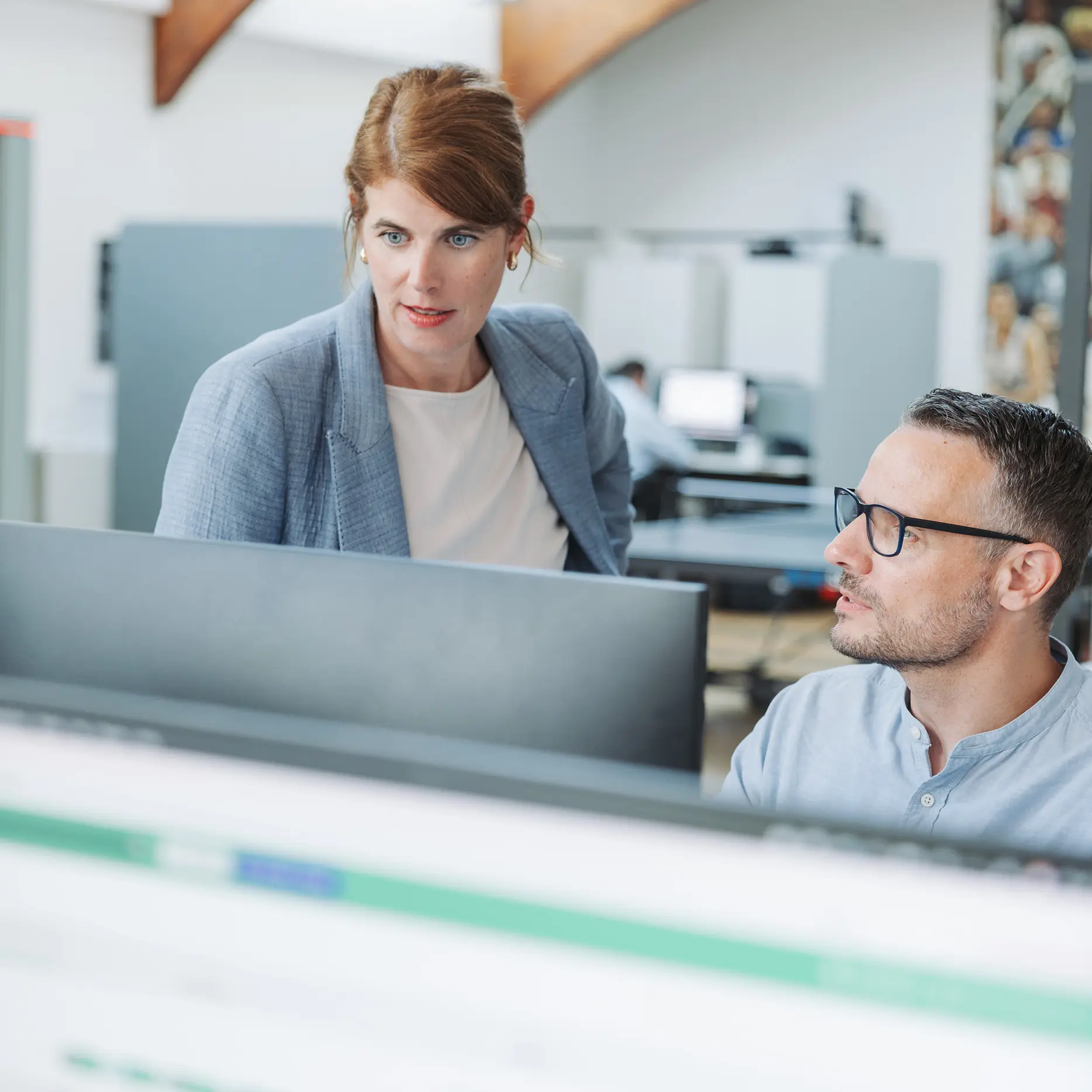 Ein Medienanalyst erklärt einer anderen Person eine aktuelle Analyse an einem Bildschirm im pressrelations Büro