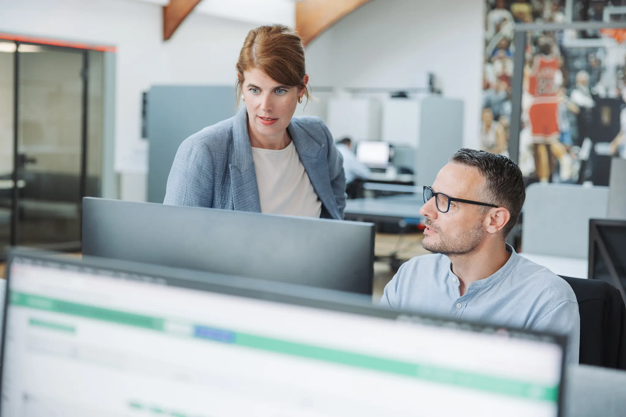 Ein Medienanalyst erklärt einer anderen Person eine aktuelle Analyse an einem Bildschirm im pressrelations Büro