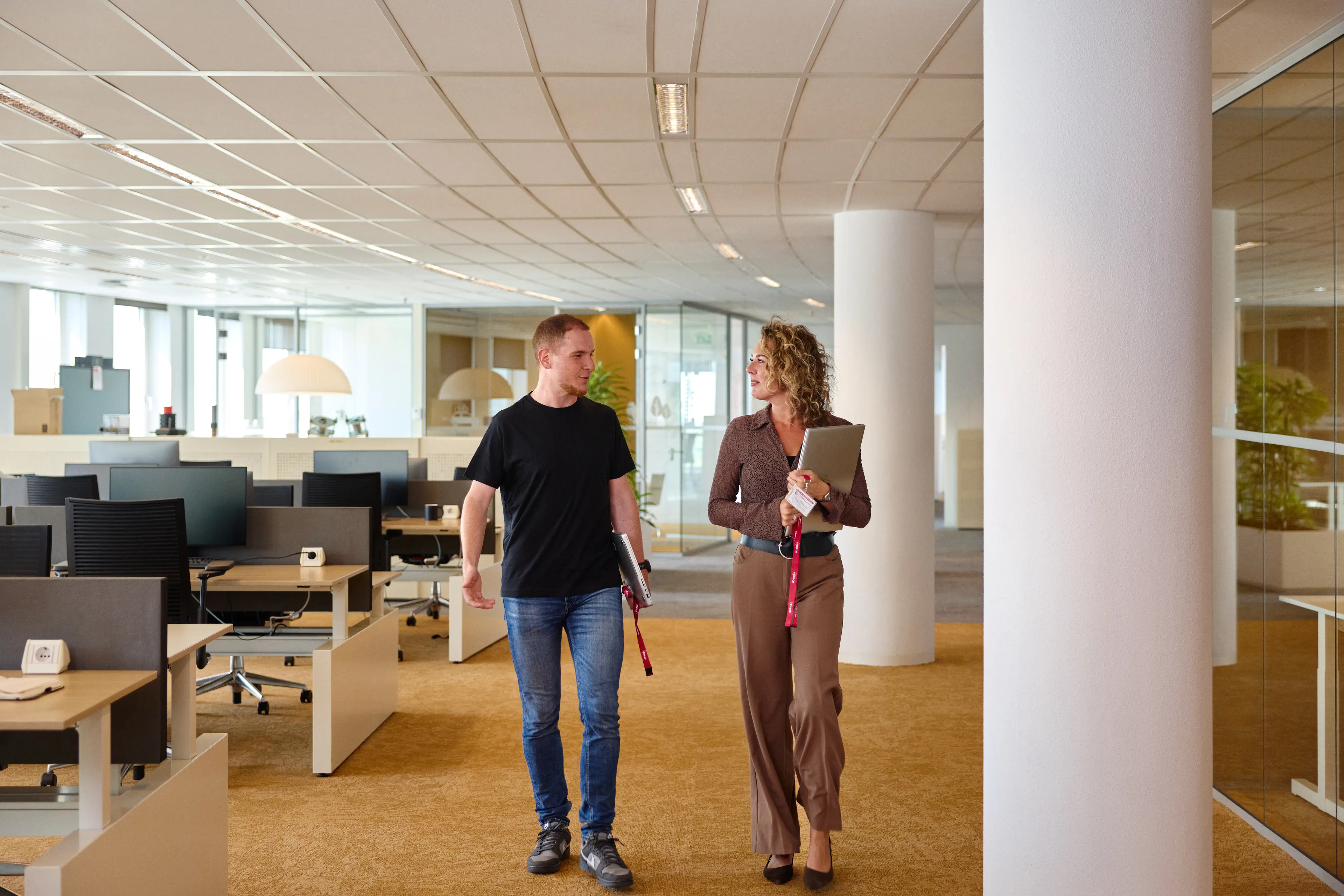 Twee collega's lopen door een open kantooromgeving