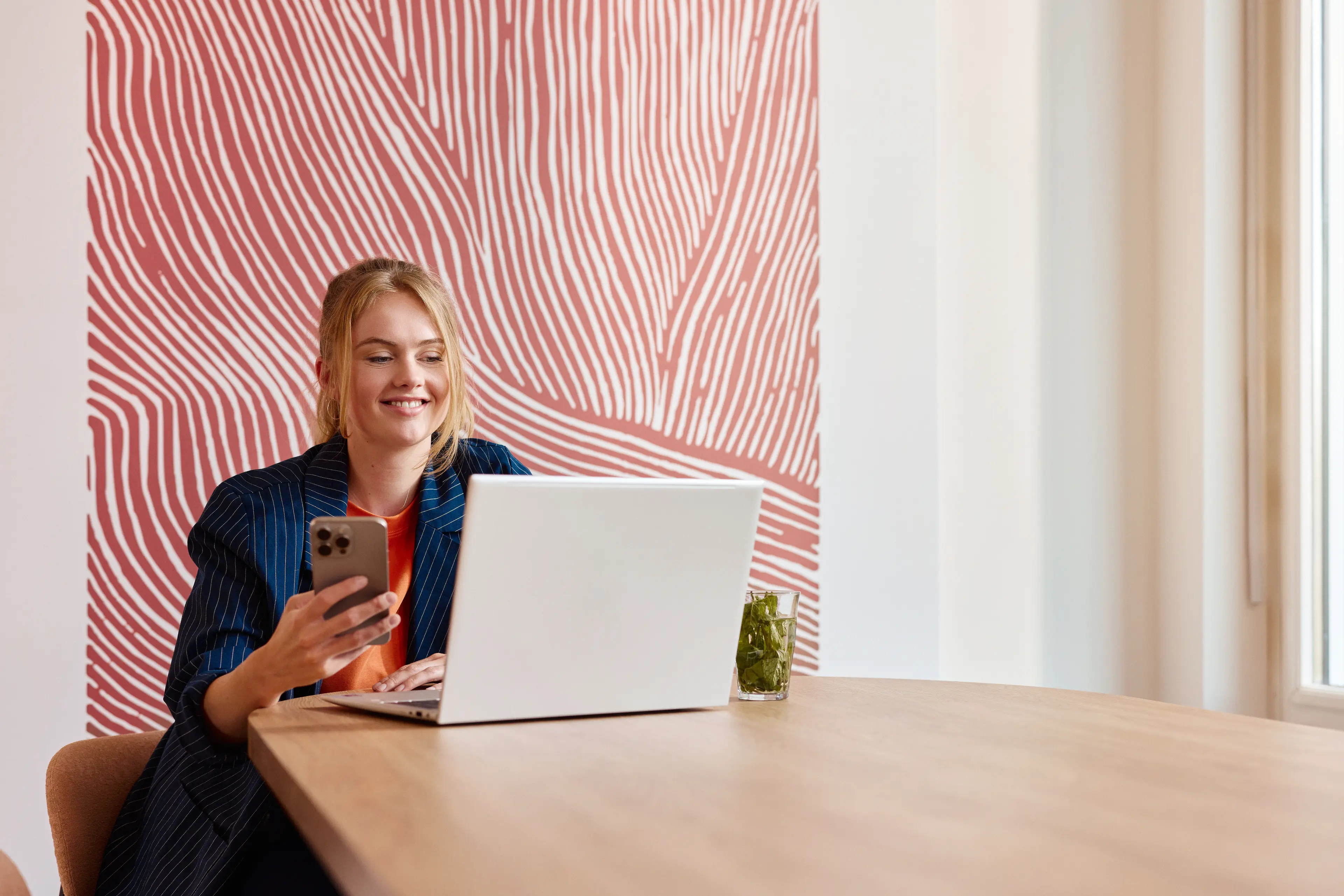 Vrouw met een laptop en telefoon aan een tafel in een kantoor