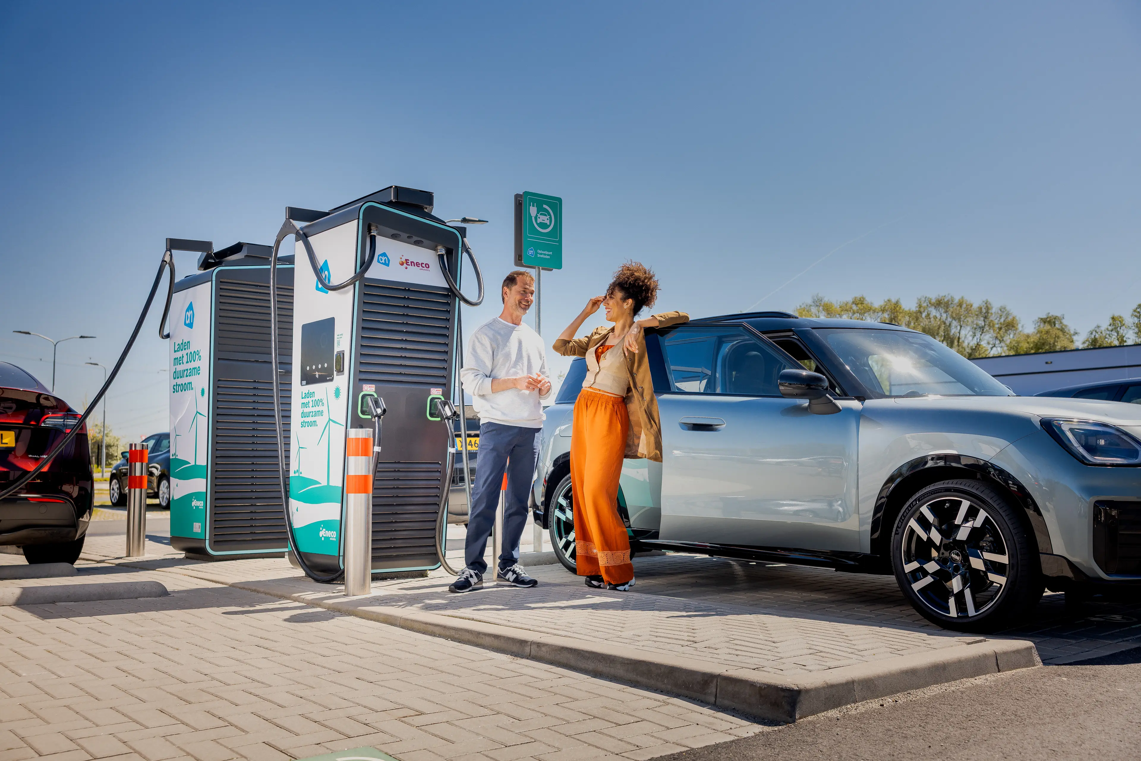 Twee mensen bij een Eneco snellader op een parkeerterrein
