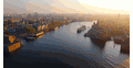 Luchtfoto van de grachten van Amsterdam bij zonsopgang met historische panden en boten op het water.