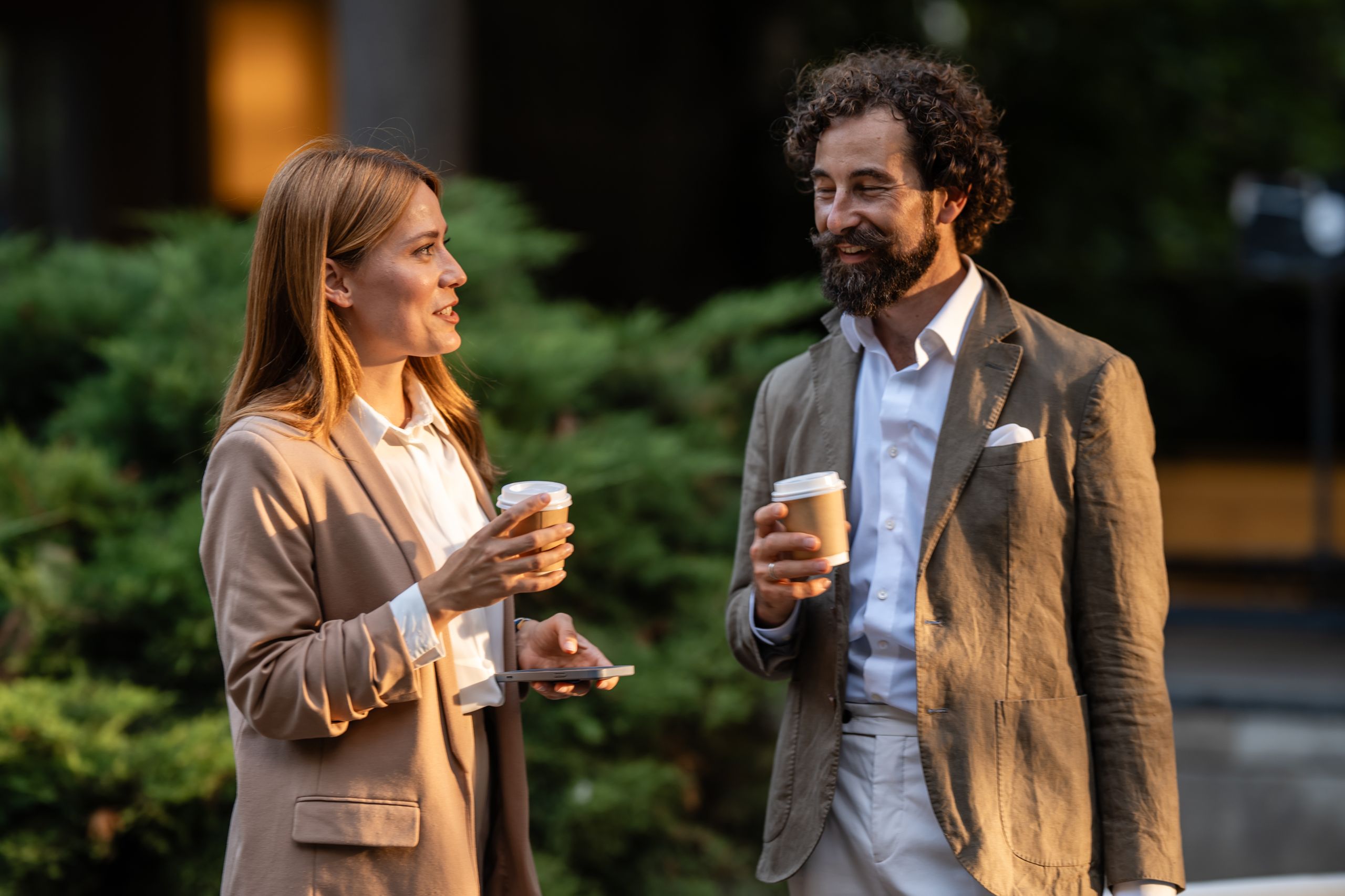 En man och en kvinna står utomhus och dricker kaffe tillsammans.