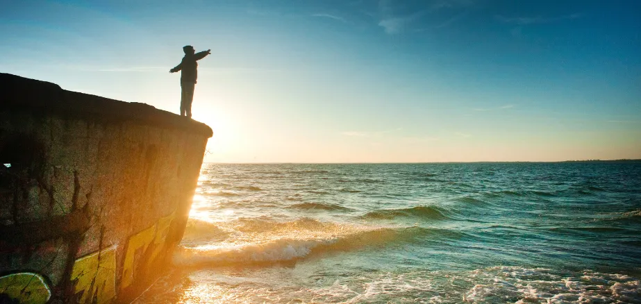 Person standing on a cliff above the sea