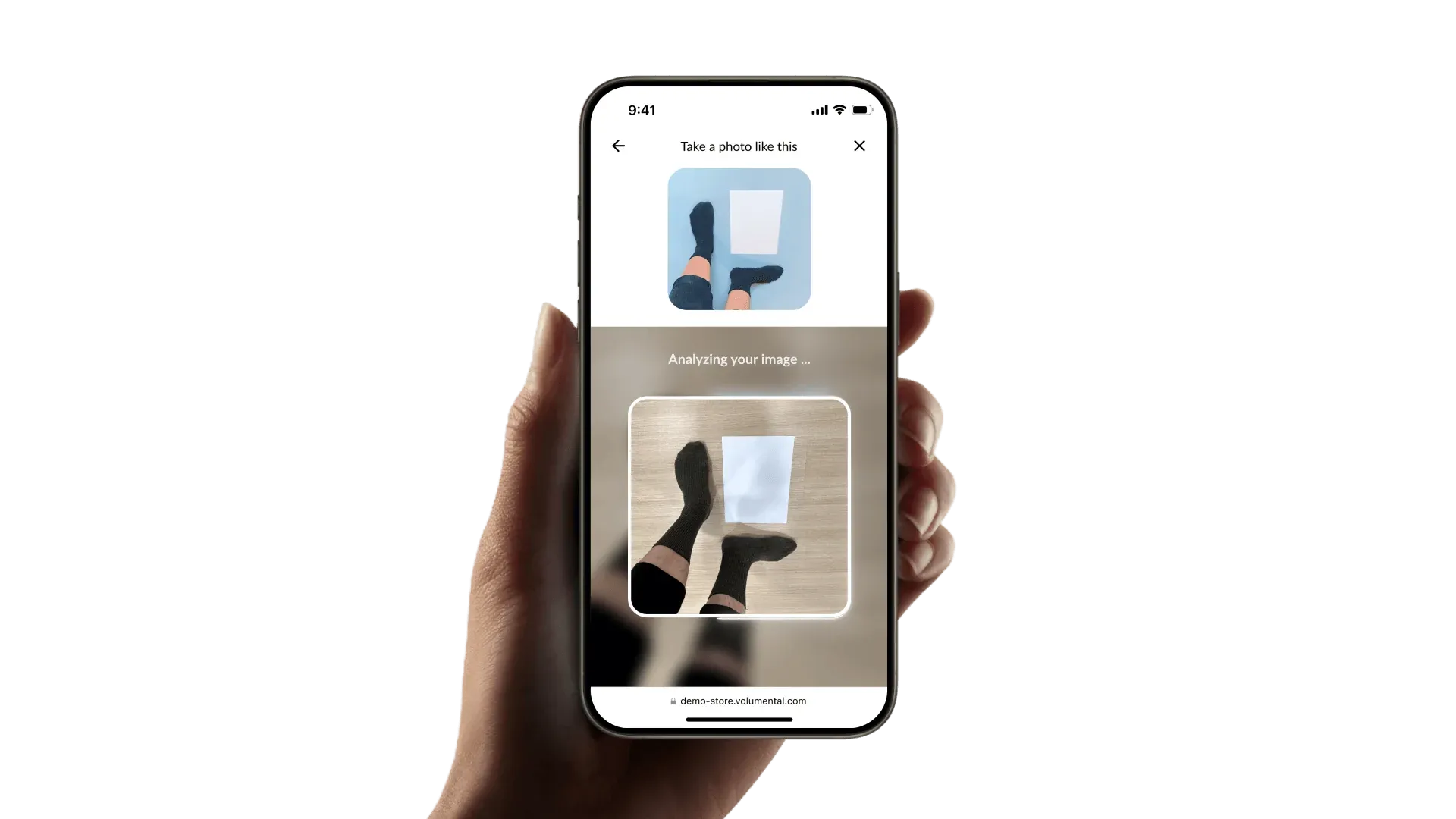 Hand holding a smartphone displaying an app interface for capturing and analyzing a photo of feet wearing black socks on a wooden floor.