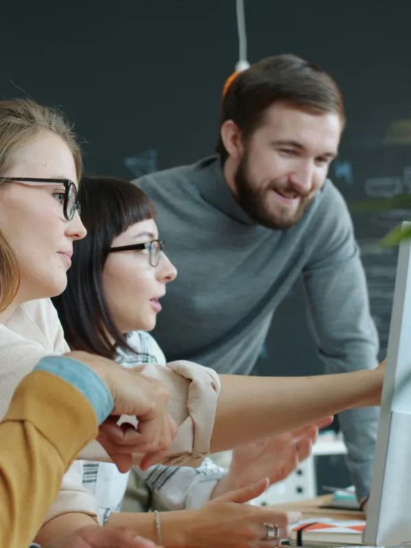 Coworkers looking at a report on a monitor together