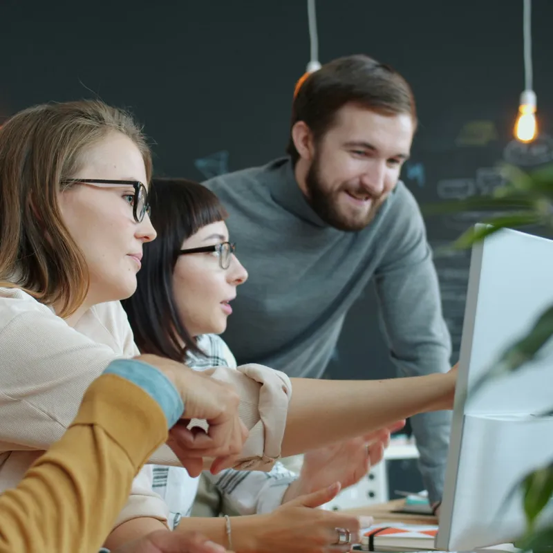 Coworkers looking at a report on a monitor together