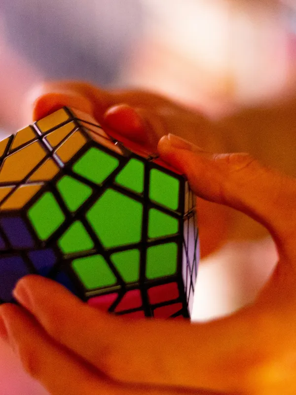 "A solved 3x3 Rubik's Cube placed on a wooden surface, brightly lit with soft natural light, highlighting its colorful red, blue, green, yellow, orange and white tiles.