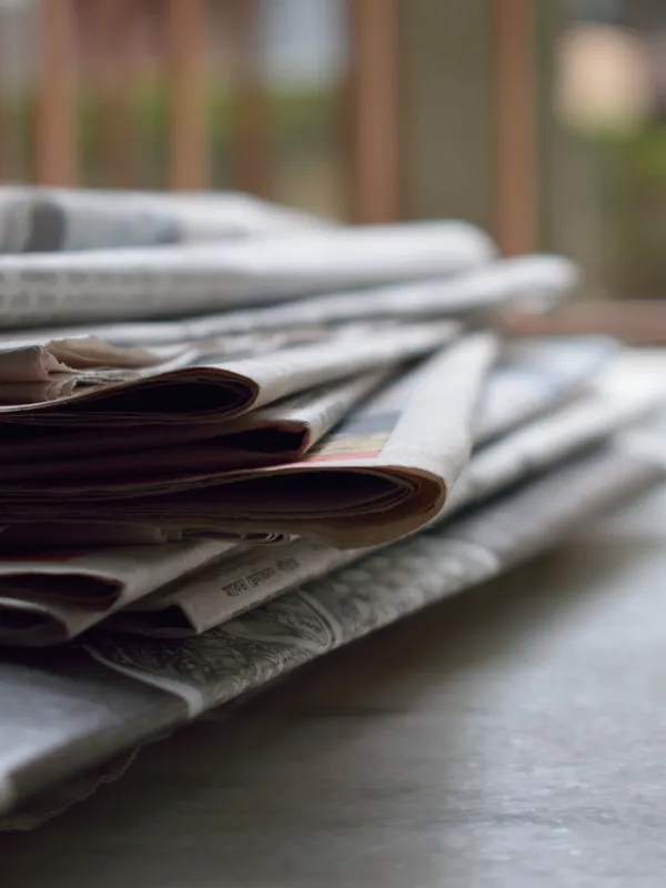 stack of magazines and newspapers sitting on a desk.